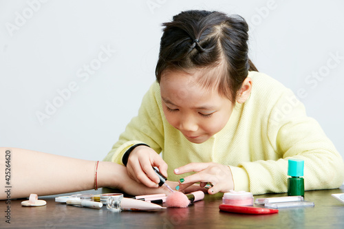 Asian little girl doing makeup on herself in fun