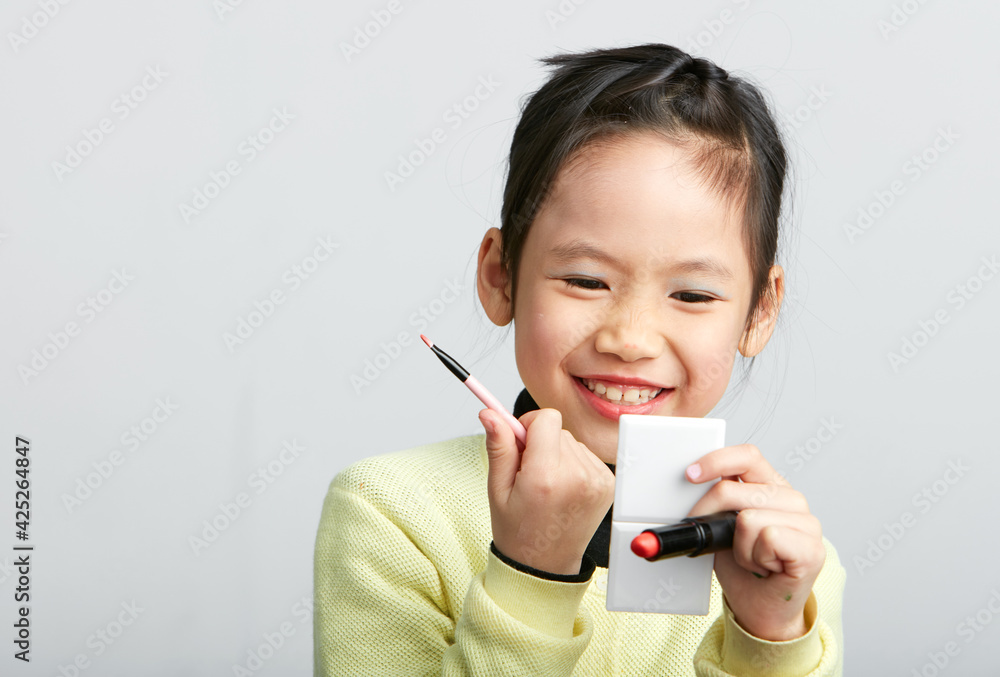 Asian little girl doing makeup on herself in fun Asian little girl doing makeup on herself in fun