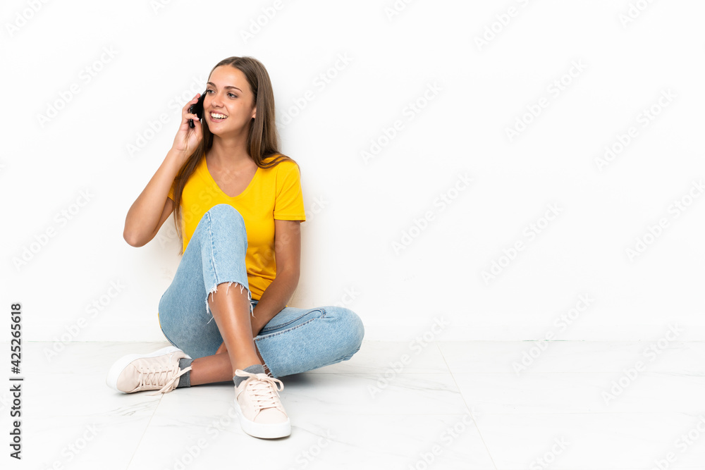 Young girl sitting on the floor keeping a conversation with the mobile phone Young girl sitting on the floor keeping a conversation with the mobile phone