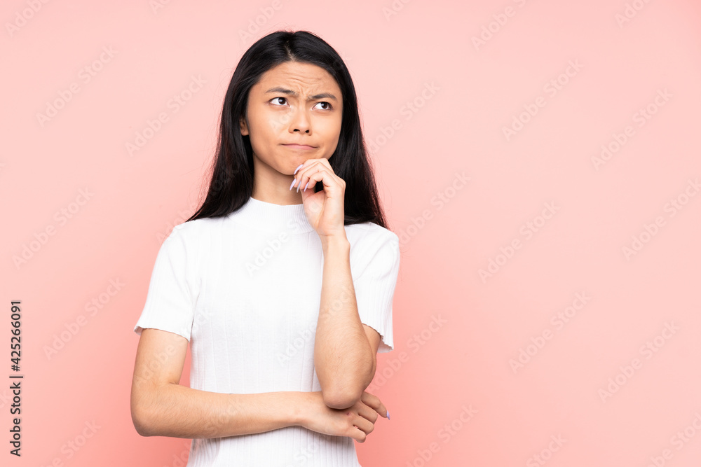 Teenager Chinese woman isolated on pink background having doubts and thinking Teenager Chinese woman isolated on pink background having doubts and thinking