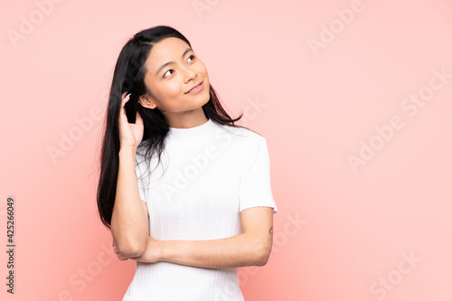 Teenager Chinese woman isolated on pink background thinking an idea