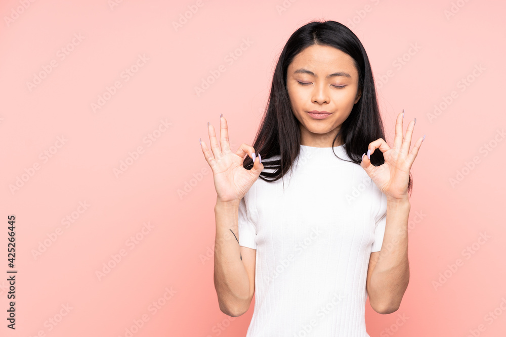 Teenager Chinese woman isolated on pink background in zen pose Teenager Chinese woman isolated on pink background in zen pose