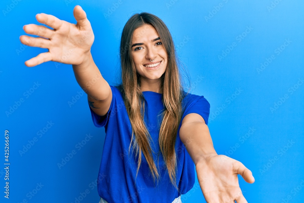 Fototapeta premium Young hispanic woman wearing casual clothes looking at the camera smiling with open arms for hug. cheerful expression embracing happiness.