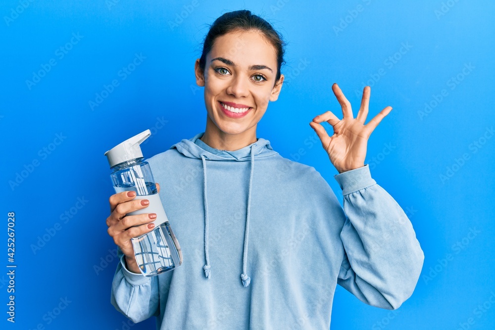 Young caucasian blonde woman drinking bottle of water doing ok sign with fingers, smiling friendly gesturing excellent symbol Young caucasian blonde woman drinking bottle of water doing ok sign with fingers, smiling friendly gesturing excellent symbol