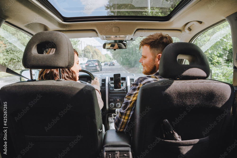 couple sitting in car driving to travel destination - obrazy, fototapety, plakaty 