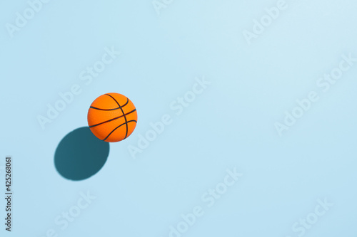 Orange basketball ball, hovering over pastel blue background. Minimal image with copy space, top view © Ramil Gibadullin