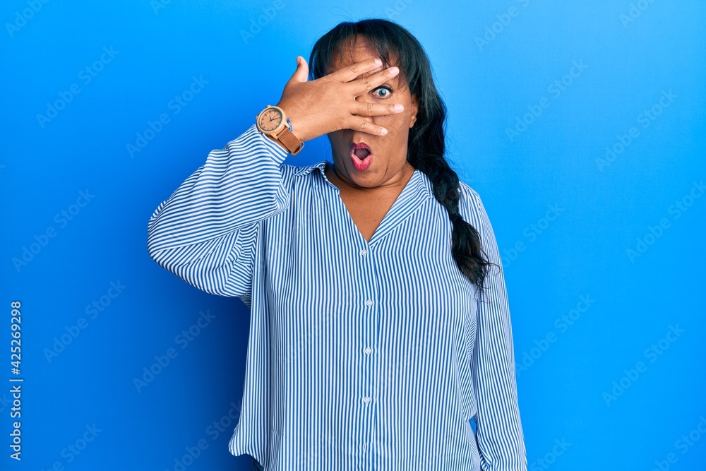 Middle age african american woman wearing casual clothes peeking in shock covering face and eyes with hand, looking through fingers afraid Middle age african american woman wearing casual clothes peeking in shock covering face and eyes with hand, looking through fingers afraid