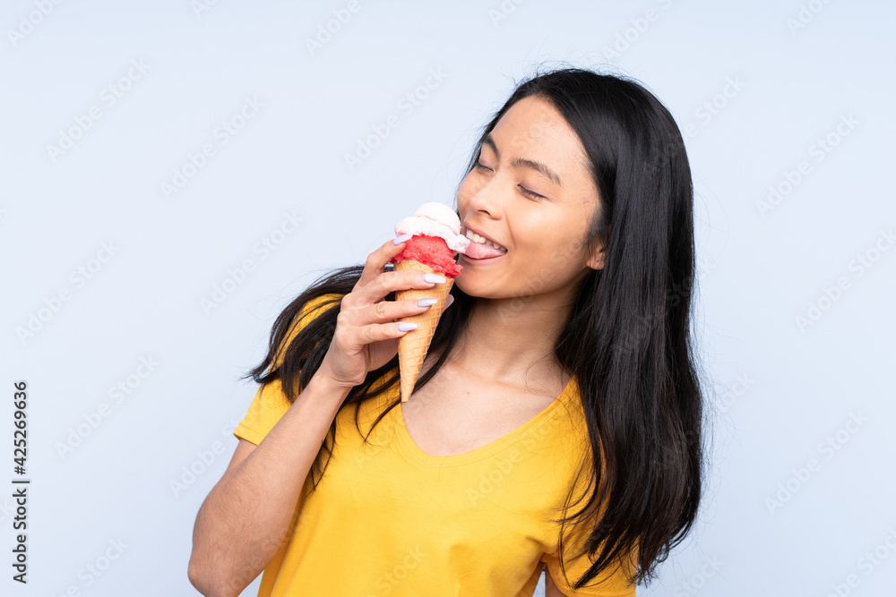 Teenager Asian girl with a cornet ice cream isolated on blue background