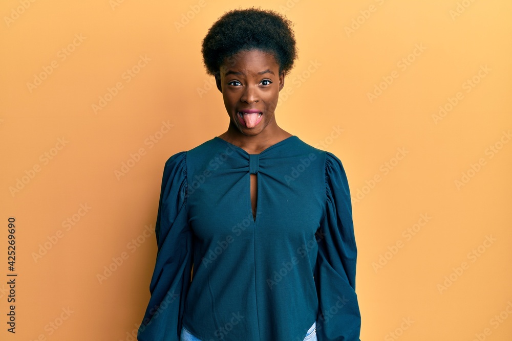 Obraz premium Young african american girl wearing casual clothes sticking tongue out happy with funny expression. emotion concept.