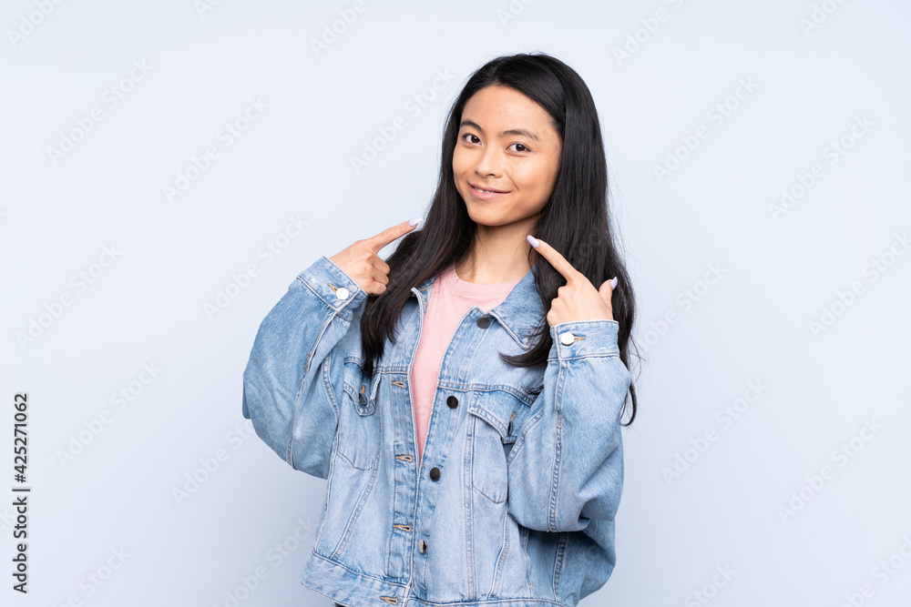 Teenager Chinese woman isolated on blue background giving a thumbs up gesture Teenager Chinese woman isolated on blue background giving a thumbs up gesture