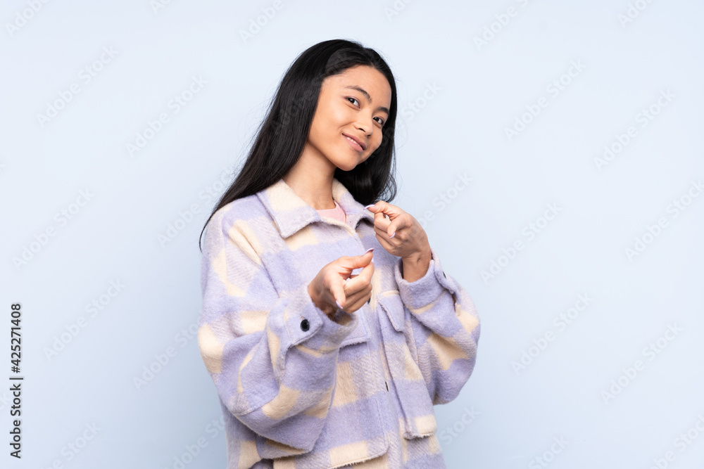 Teenager Chinese woman isolated on blue background surprised and pointing front Teenager Chinese woman isolated on blue background surprised and pointing front