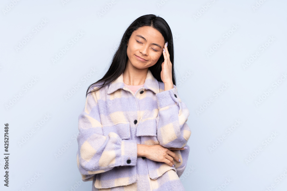 Teenager Chinese woman isolated on blue background with headache Teenager Chinese woman isolated on blue background with headache