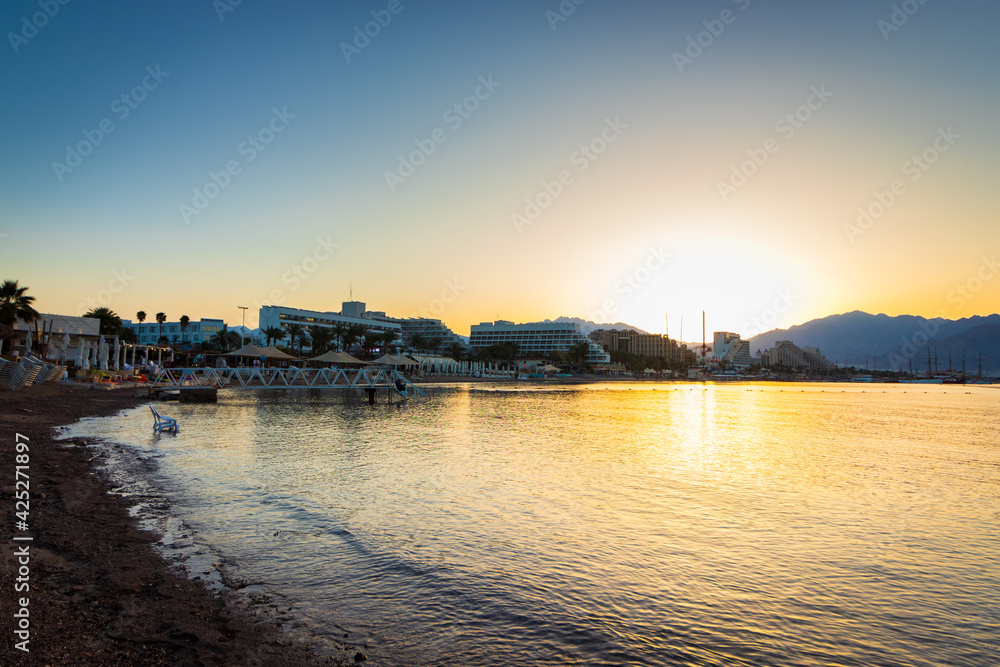The beach in Eilat, empty of people at sunrise, in the background of the hotels and the promenade, Israel