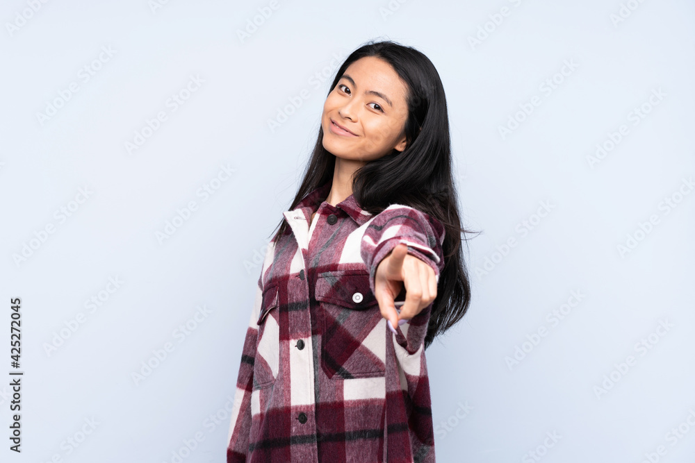 Teenager Chinese woman isolated on blue background pointing front with happy expression Teenager Chinese woman isolated on blue background pointing front with happy expression