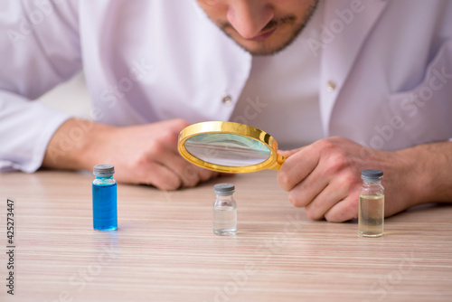 Young male chemist doctor holding vial