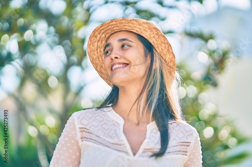 Young hispanic tourist woman wearing summer hat standing at the park. © Krakenimages.com