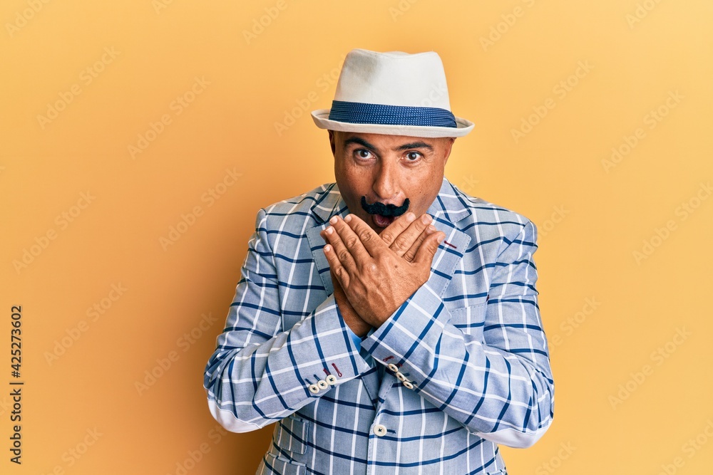 Mature middle east man with mustache wearing vintage and elegant fashion style shocked covering mouth with hands for mistake. secret concept.