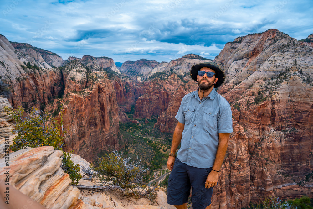 A young man enjoying the views of Zion from the Angels Landing Trail in Zion National Park, Utah. United States.