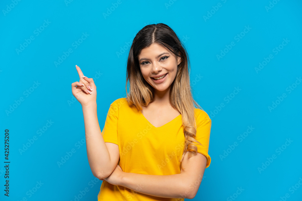 Young Russian girl isolated on blue background pointing up a great idea