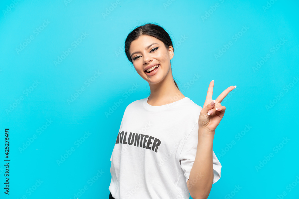 Young Russian volunteer girl isolated on blue background smiling and showing victory sign Young Russian volunteer girl isolated on blue background smiling and showing victory sign