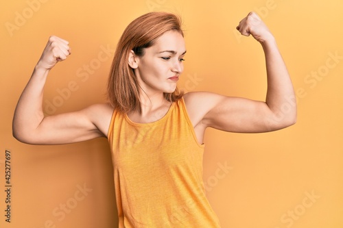 Stampa su tela Young caucasian woman wearing casual style with sleeveless shirt showing arms muscles smiling proud