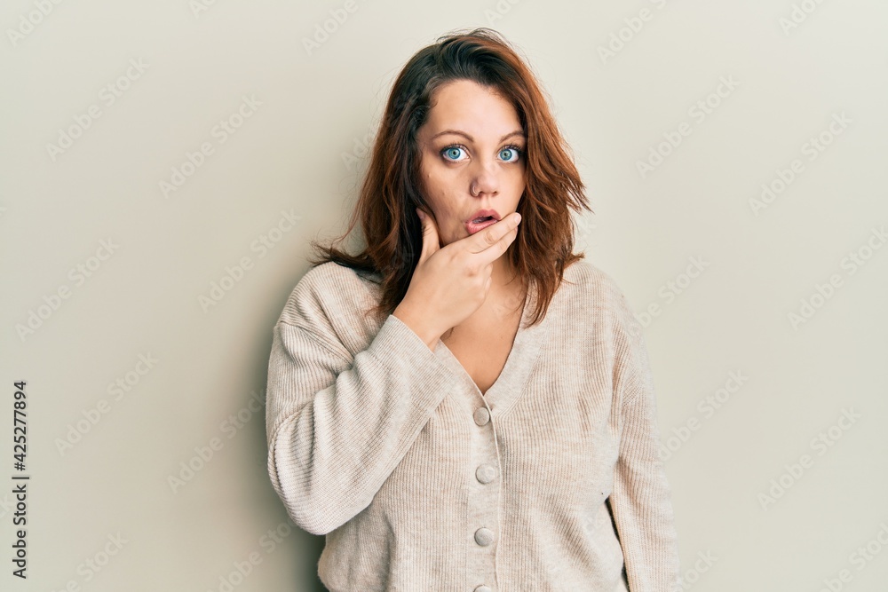 Young caucasian woman wearing casual clothes looking fascinated with disbelief, surprise and amazed expression with hands on chin Young caucasian woman wearing casual clothes looking fascinated with disbelief, surprise and amazed expression with hands on chin