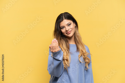 Young Russian girl isolated on yellow background inviting to come with hand. Happy that you came © luismolinero