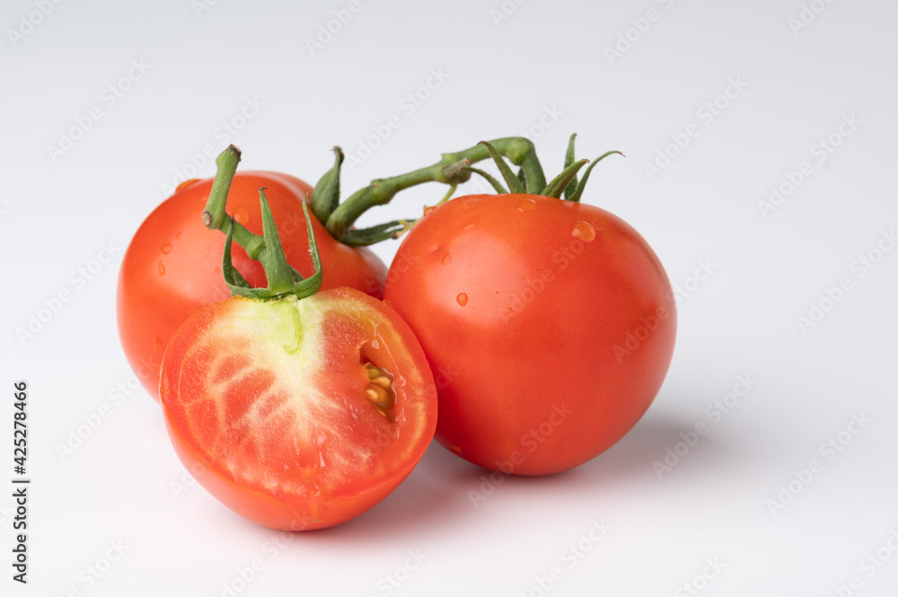 Fresh tomatoes on a green stem on white Fresh tomatoes on a green stem on white