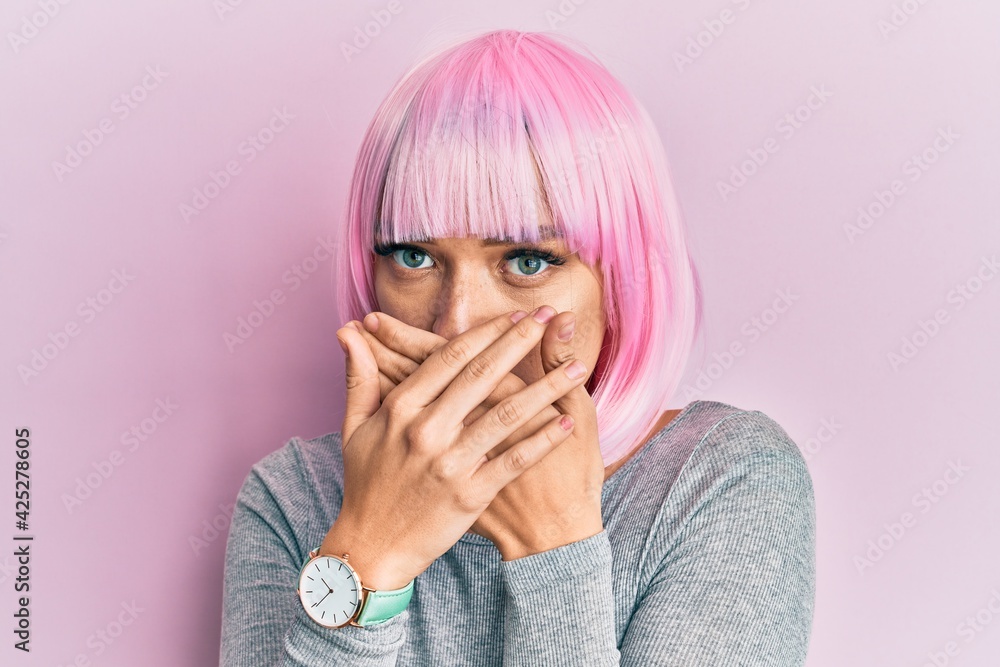 Young caucasian woman wearing pink wig shocked covering mouth with hands for mistake. secret concept. Young caucasian woman wearing pink wig shocked covering mouth with hands for mistake. secret concept.