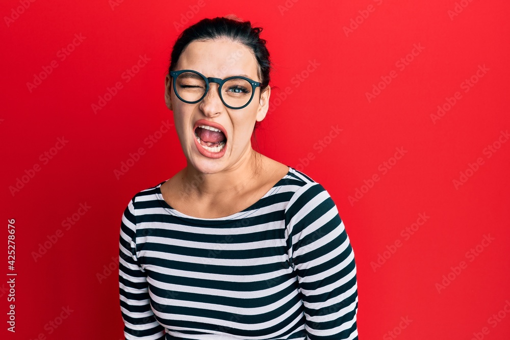 Young caucasian woman wearing casual clothes and glasses winking looking at the camera with sexy expression, cheerful and happy face.
