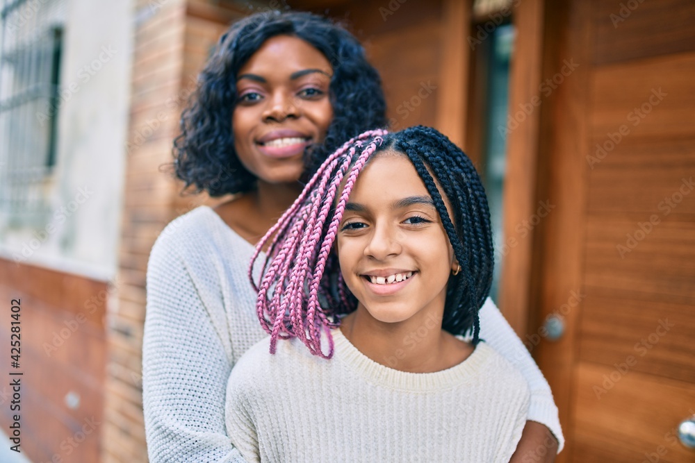 Beautiful african american mother and daughter smiling happy and hugging. Standing with smile on face standing at the city. Beautiful african american mother and daughter smiling happy and hugging. Standing with smile on face standing at the city.