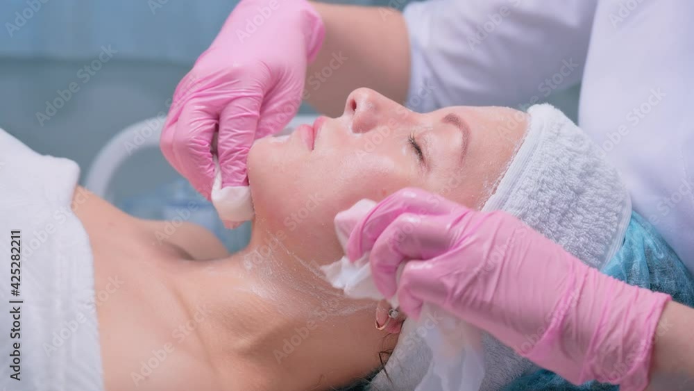 Cosmetologist performs the procedure of cleansing and moisturizing the skin Cosmetologist performs the procedure of cleansing and moisturizing the skin