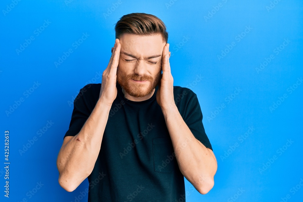 Fototapeta premium Young redhead man wearing casual black t shirt with hand on head, headache because stress. suffering migraine.
