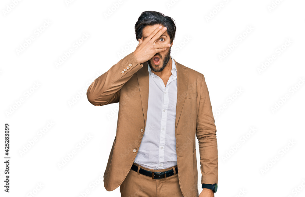 Young hispanic man wearing business clothes peeking in shock covering face and eyes with hand, looking through fingers with embarrassed expression. Young hispanic man wearing business clothes peeking in shock covering face and eyes with hand, looking through fingers with embarrassed expression.