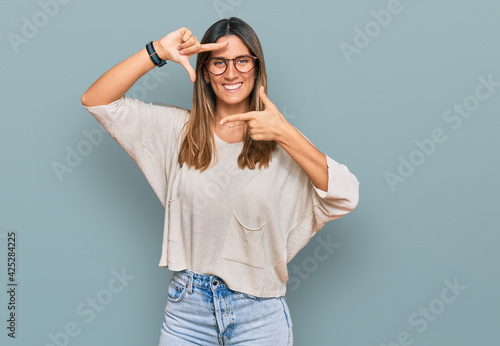 Young woman wearing casual clothes and glasses smiling making frame with hands and fingers with happy face. creativity and photography concept.
