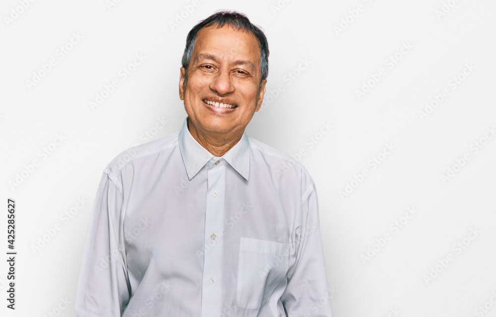 Middle age indian man wearing casual white shirt looking positive and happy standing and smiling with a confident smile showing teeth Middle age indian man wearing casual white shirt looking positive and happy standing and smiling with a confident smile showing teeth