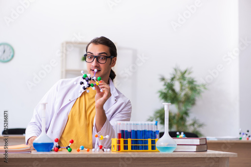 Young male chemist studying molecular model in the classroom