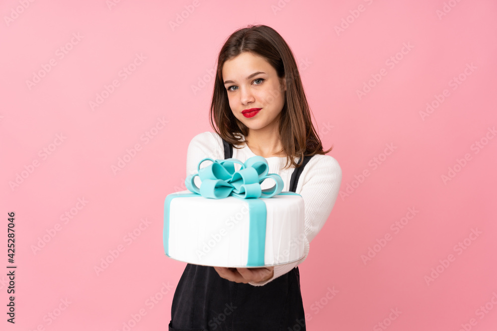 Girl holding a big cake isolated on pink background with happy expression Girl holding a big cake isolated on pink background with happy expression