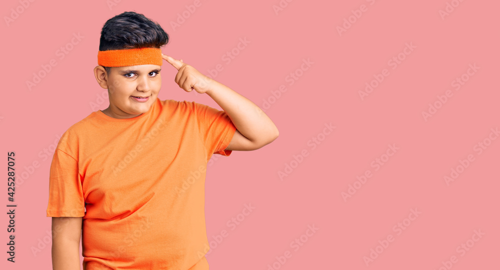 Little boy kid wearing sportswear smiling pointing to head with one finger, great idea or thought, good memory
