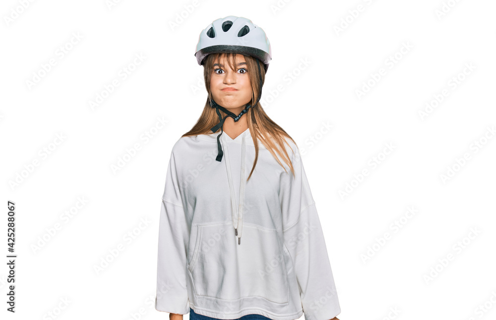 Teenager caucasian girl wearing bike helmet puffing cheeks with funny face. mouth inflated with air, crazy expression. Teenager caucasian girl wearing bike helmet puffing cheeks with funny face. mouth inflated with air, crazy expression.