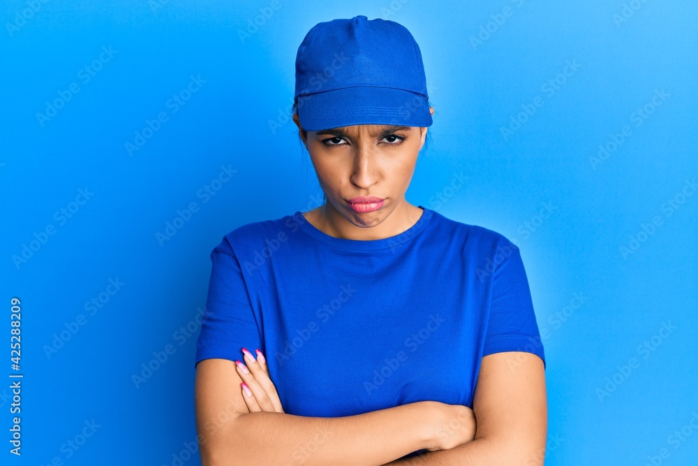 Beautiful brunette woman wearing delivery uniform skeptic and nervous, disapproving expression on face with crossed arms. negative person.