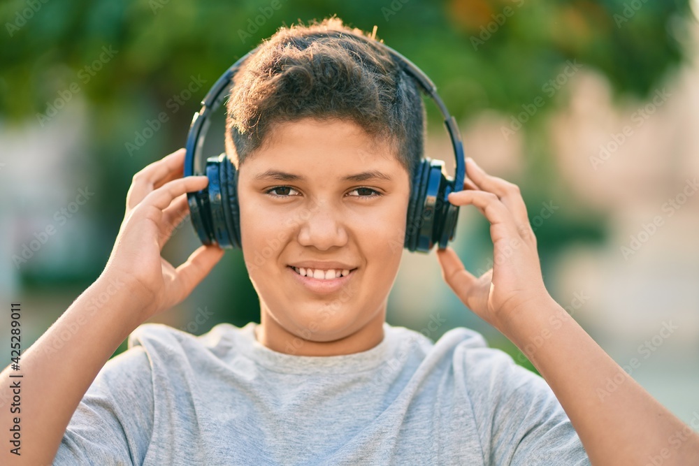 Adorable latin boy smiling happy using headphones at the city. Adorable latin boy smiling happy using headphones at the city.