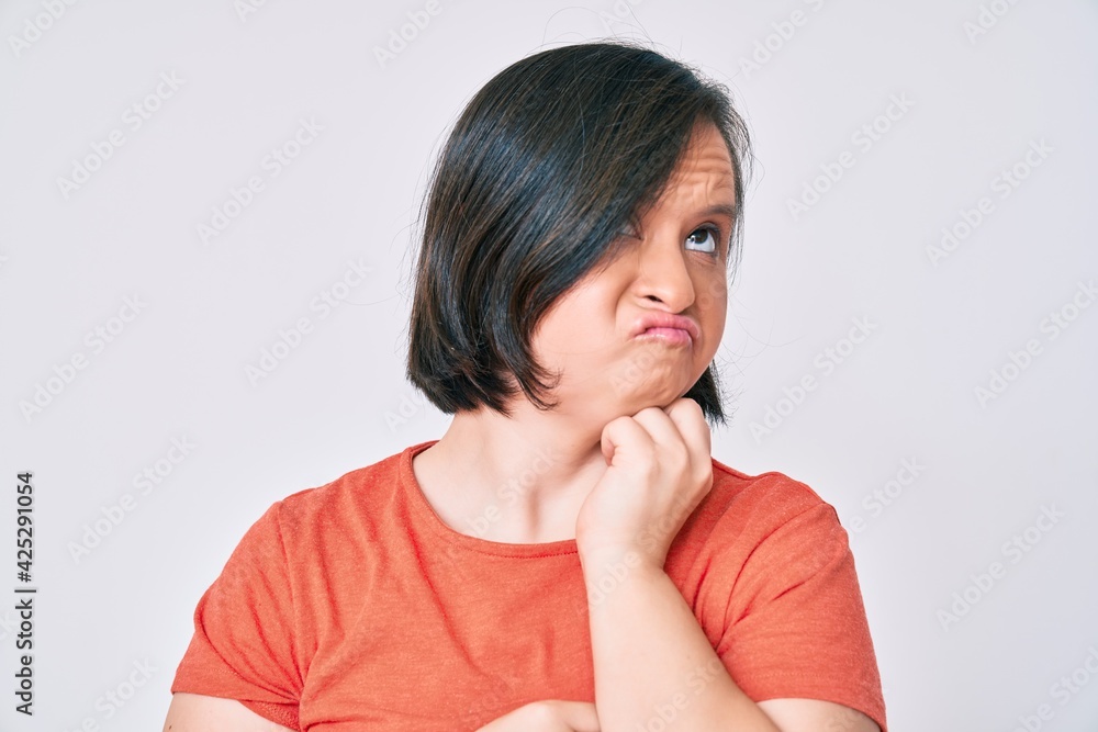 Brunette woman with down syndrome wearing casual clothes serious face thinking about question with hand on chin, thoughtful about confusing idea Brunette woman with down syndrome wearing casual clothes serious face thinking about question with hand on chin, thoughtful about confusing idea
