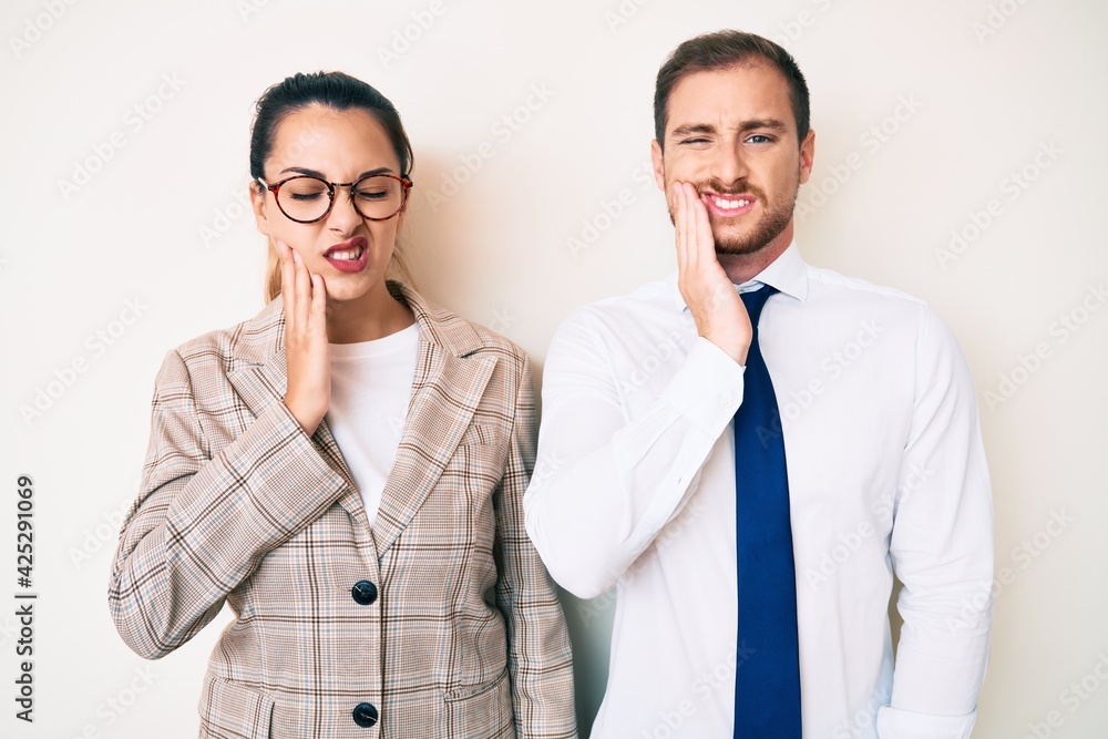 Beautiful couple wearing business clothes touching mouth with hand with painful expression because of toothache or dental illness on teeth. dentist Beautiful couple wearing business clothes touching mouth with hand with painful expression because of toothache or dental illness on teeth. dentist