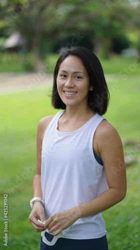 Asian chinese woman smiling sweetly outdoors garden active sporty holding mask
