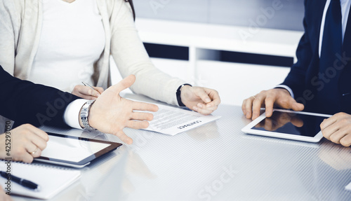 Business people working together at meeting in modern office. Unknown businessman and woman with colleagues or lawyers at negotiation about contract