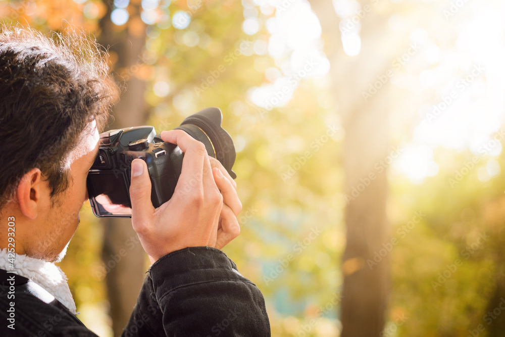 Taking photos in autumn season. Student taking pictures of a fall forest with a bright sunlight. Taking photos in autumn season. Student taking pictures of a fall forest with a bright sunlight.
