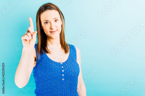 beautiful young woman looking straight ahead showing a finger. index finger. pointing up