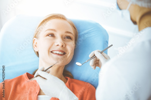 Happy woman is being examined by dentist at dental clinic. Healthy teeth and medicine  stomatology concept