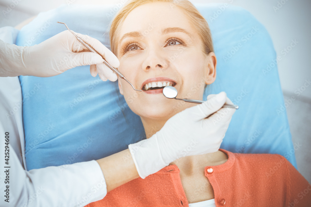 Happy woman is being examined by dentist at dental clinic. Healthy teeth and medicine, stomatology concept Happy woman is being examined by dentist at dental clinic. Healthy teeth and medicine, stomatology concept